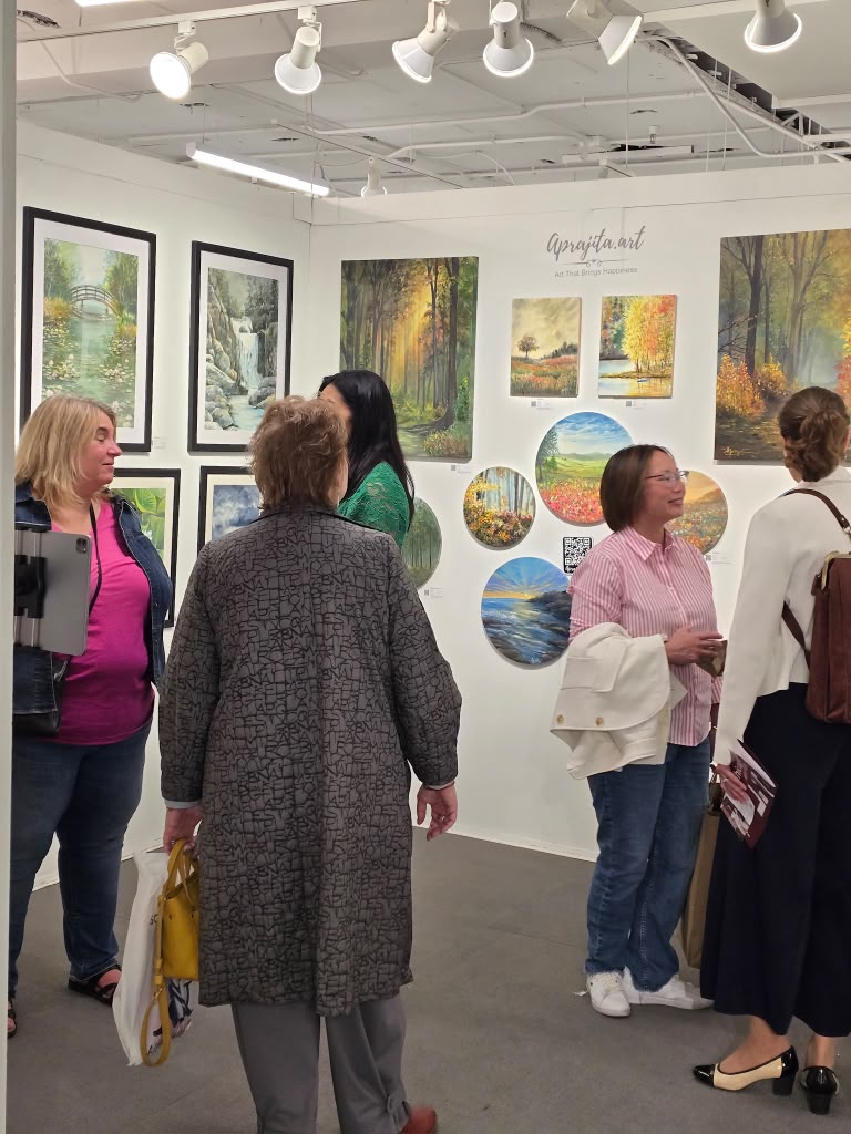 Visitors in conversation in front of a wall of paintings
