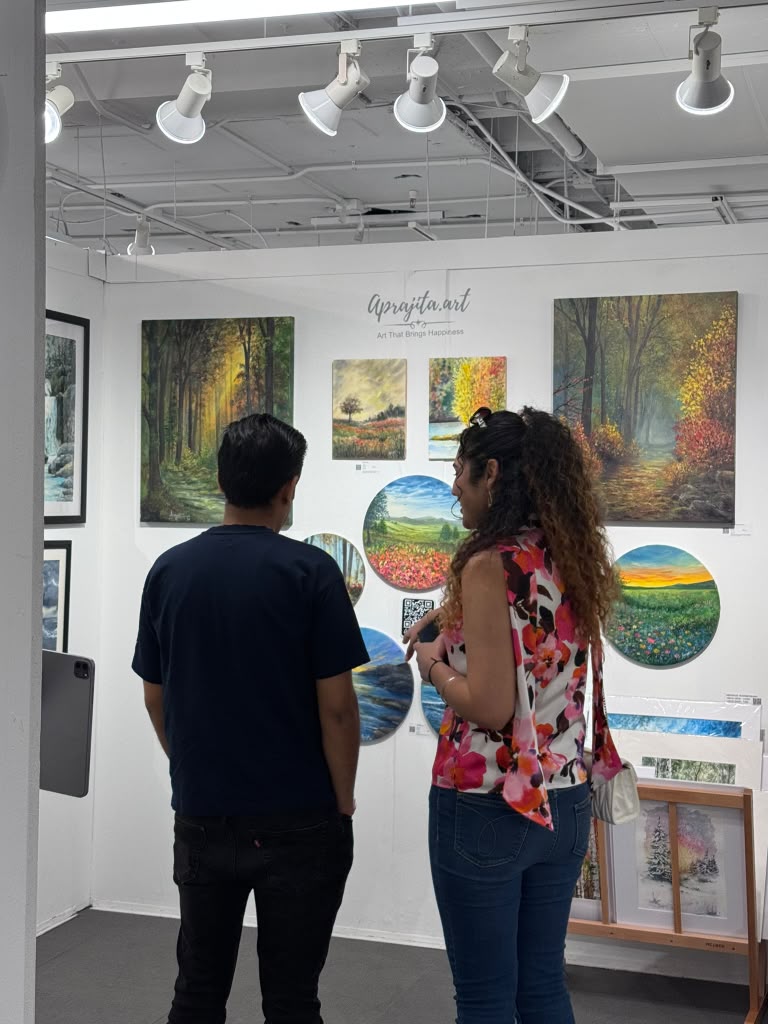 Visitors studying a wall of landscape paintings